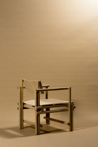 Ein Holzstuhl mit minimalistischem Design steht auf einem schlichten beigen Hintergrund unter sanfter Beleuchtung.