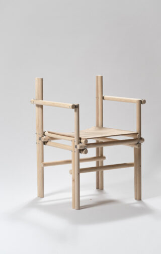 Ein minimalistischer Holzstuhl mit zylindrischen Stangen für Beine, Armlehnen und Rückenlehne, die durch sichtbare Verschlüsse verbunden sind, auf einem schlichten hellen Hintergrund.