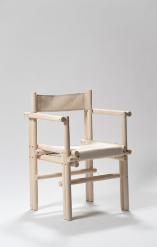 Ein minimalistischer Holzstuhl mit zylindrischen Beinen und Rahmen, Sitzfläche und Rückenlehne aus Segeltuch vor einem schlichten hellen Hintergrund.