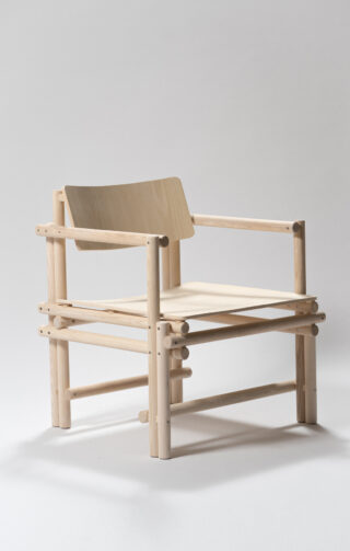 Ein minimalistischer Holzstuhl mit hellem Holzrahmen, flacher Sitzfläche und abgewinkelter Rückenlehne, mit sichtbaren Dübelverbindungen und einem schlichten, modernen Design.