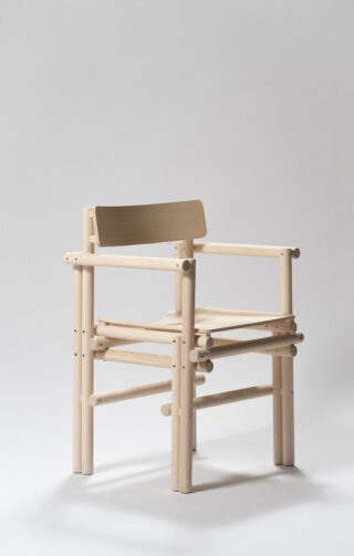 Ein minimalistischer Holzstuhl mit gerader Rückenlehne, flacher Sitzfläche und zylindrischen Beinen und Stützen vor einem schlichten hellen Hintergrund.