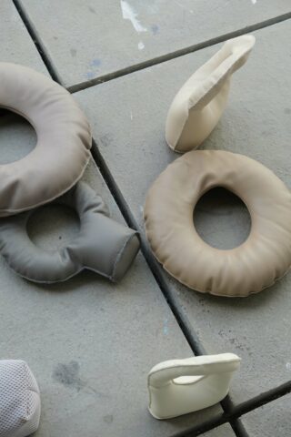 Auf einer gefliesten Betonoberfläche liegen vier runde Polsterkissen und zwei kleine Polsterobjekte.