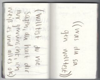 Ein aufgeschlagenes Notizbuch mit handgeschriebenem deutschen Text in schwarzer Tinte auf zwei Seiten. Auf der linken Seite steht: „(wolltest du nie sagen, du hast dir nur gewünscht, ich weiß es und alles ok)“, auf der rechten Seite: „(was du sagen wolltest)“.