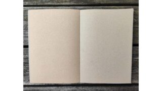 Ein offenes Notizbuch mit leeren braunen Seiten liegt auf einer Holzoberfläche.
