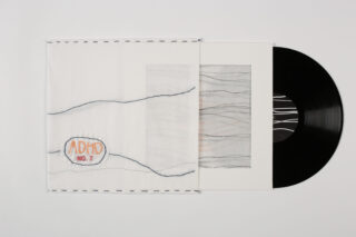 Eine Vinyl-Schallplatte gleitet teilweise aus einer weißen Hülle mit aufgenähten Linien und einem Aufnäher mit der Aufschrift „ADHD NO. 7“; auf der Innenseite des Covers ist ein abstraktes Kunstwerk zu sehen.