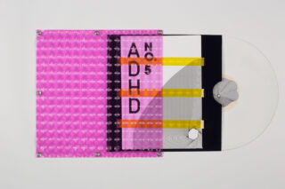Eine durchsichtige Vinyl-Schallplatte, teilweise in einer Hülle mit geometrischen, abstrakten Designs und fetten Buchstaben mit der Aufschrift „ADHD No 5“ auf geschichteten farbigen und strukturierten Materialien.