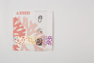 Eine Zeitschrift mit dem Titel „ADHD NO. 6“ mit abstrakten Korallen- und Tupfenmustern in Pink, Orange und holografischen Farben auf einem schlichten weißen Hintergrund.