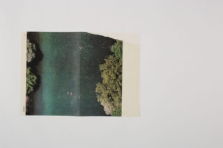 Auf einem schlichten weißen Hintergrund ist ein kleines rechteckiges Foto eines von Bäumen gesäumten Flusses mit einigen schwimmenden Menschen platziert.