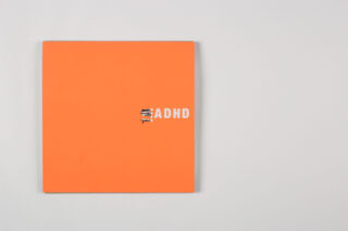 Ein orangefarbenes quadratisches Objekt mit dem Wort „ADHS“ in weißen Buchstaben, wobei kleine Figuren auf den ersten Buchstaben klettern, vor einem schlichten hellgrauen Hintergrund.