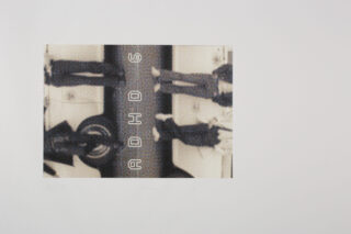 Ein gedrehtes, körniges Schwarzweißfoto von vier Personen, die neben einem Auto stehen. In der Mitte steht vertikal der Text „ADHOG“. Das Bild ist vor einem schlichten weißen Hintergrund platziert.