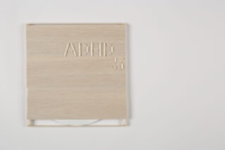 Eine CD-Hülle aus hellem Holz mit der Prägung „ACHP 5“ auf der Vorderseite, die teilweise den Blick auf eine weiße CD im Inneren freigibt, vor einem schlichten weißen Hintergrund.