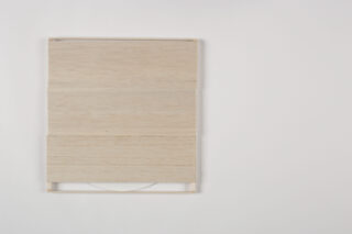 Eine quadratische Holzhülle mit horizontalen Lamellen gibt den Blick teilweise auf eine weiße CD im Inneren frei, die vor einem schlichten weißen Hintergrund platziert ist.