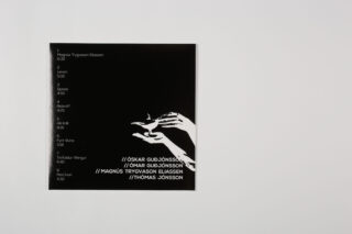 Schwarzes Albumcover mit weißem Text, der Songtitel und Künstler auflistet; auf der rechten Seite erscheint vor dem schwarzen Hintergrund eine weiße Grafik von Händen, die einen Vogel halten.