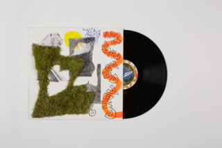 Eine Vinyl-Schallplatte gleitet teilweise aus einem Albumcover mit abstrakten Mustern heraus, darunter eine grasähnliche Textur, Bergbilder und orangefarbener handgeschriebener Text.
