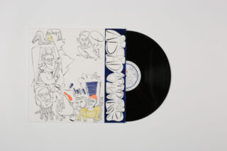 Eine schwarze Vinyl-Schallplatte, teilweise aus einer weißen, illustrierten Hülle mit Cartoon-Zeichnungen und dem Wort „ADVENTURE“ in fetten Buchstaben auf dem Cover.