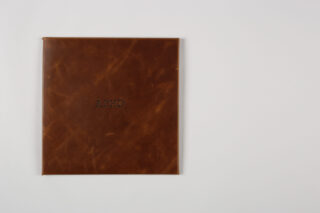 Ein in braunes Leder gebundenes Buch mit der Prägung „ADHS“ auf dem Einband, platziert auf einer schlichten weißen Oberfläche.