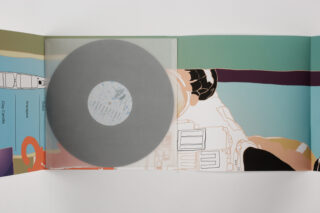 Eine durchscheinende graue Vinyl-Schallplatte, die teilweise farbenfrohe abstrakte Kunstwerke in einer offenen Schallplattenhülle bedeckt.