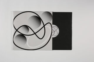 Eine schwarze Vinyl-Schallplatte gleitet teilweise aus einer schwarzen Hülle mit einem abstrakten, monochromen Cover mit geschwungenen schwarzen Linien und schattierten Kreisen auf hellem Hintergrund.