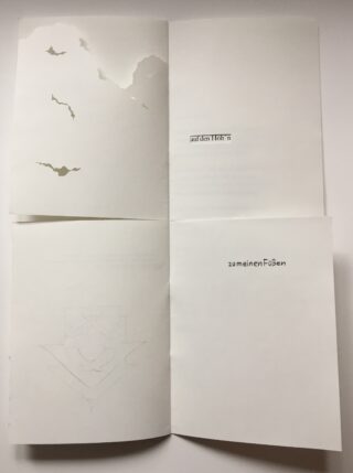 Ein aufgeschlagenes Heft zeigt auf der oberen linken Seite Silhouetten fliegender Fledermäuse und auf den rechten Seiten deutschen Text: „auf den Flöh“ und „zu meinen Füßen“.