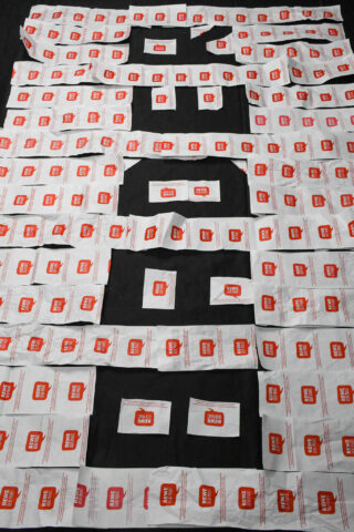 Dutzende weiße und rote Gewürzpackungen zum Mitnehmen sind in einem Gittermuster auf einer dunklen Oberfläche angeordnet.