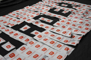 Päckchen mit der typischen Sauce von Chick-fil-A sind in Reihen auf einer schwarzen Oberfläche angeordnet und bilden große Blockbuchstaben.