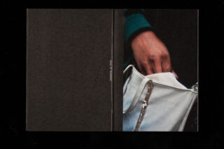 Eine Nahaufnahme der Hand einer Person, die in eine weiße Tasche greift, mit einem dunklen, schlichten Hintergrund auf der linken Seite des Bildes.