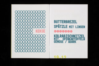 Auf einer aufgeschlagenen Broschüre ist auf der linken Seite das von Kreisen umgebene Wort „KEKSE“ zu sehen, auf der rechten Seite eine deutsche Speisekarte mit den Aufschriften „Butterbrezel“, „Spätzle mit Linsen“ und „Kohlrabischnitzel“.
