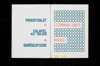 In einem aufgeschlagenen Buch ist eine Speisekarte in deutscher Sprache zu sehen, in der links die Gerichte aufgelistet sind und rechts die hervorgehobenen Gerichte „ZITRONEN-TARTE“ und „BREZEL“ zu sehen sind. Unten ist das Datum „28.12“ zu sehen.