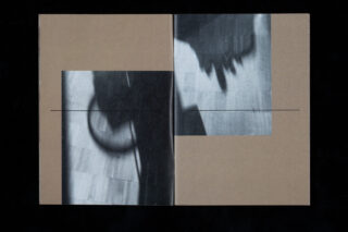 Ein offenes Buch zeigt zwei abstrakte Schwarzweiß-Schattenfotos auf braunen Seiten, die durch eine dünne horizontale Linie in der Mitte getrennt sind.