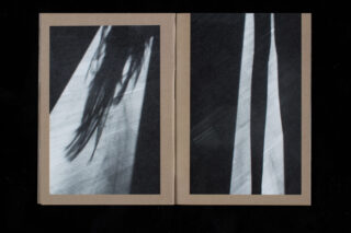 Ein offenes Buch zeigt abstrakte Schwarzweißfotografien von Schatten, die auf eine Oberfläche geworfen werden, mit länglichen und verschwommenen Formen auf beiden Seiten.