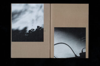 Ein offenes Buch zeigt zwei abstrakte Schwarzweißfotografien auf braunen Seiten mit schattenhaften, verschwommenen Umrissen und pflanzenähnlichen Formen.