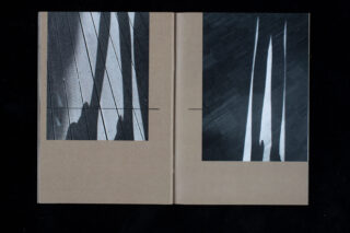 Ein offenes Buch zeigt zwei abstrakte Schwarzweißfotografien mit langgezogenen Schatten und Licht auf braunem Hintergrund.