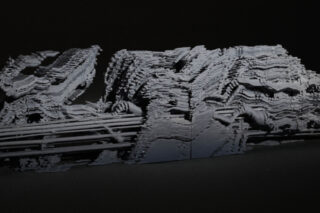 Vor einem dunklen Hintergrund wird eine vielschichtige, abstrakte weiße Skulptur mit gezackten Kanten und gerippten Texturen angezeigt.