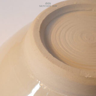 Nahaufnahme des unglasierten Bodens einer beigen Keramikschale mit konzentrischen Ringen und subtiler Textur.