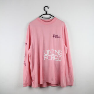 Ein hellrosa Langarmshirt mit der weißen Aufschrift „UNINSPIRED“ auf der Vorderseite und zusätzlichen Designs und Texten auf der Brust und den Ärmeln, das auf einem schwarzen Kleiderbügel vor einer weißen Wand hängt.