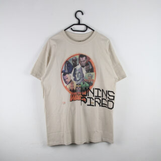 An einem schwarzen Bügel hängt ein beiges T-Shirt, darauf sind Marvel-Superhelden in einem Kreis und der Schriftzug „SECRET WARS“ abgebildet, schräg darüber ist rechts unten der Text „INSPIRED“ aufgedruckt.