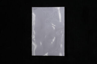 Ein geschlossenes, glänzendes, hellgraues Buch mit dem Titel „New Flows Later“ in kleiner Schrift in der oberen linken Ecke vor schwarzem Hintergrund.