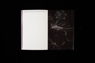 Ein offenes Buch auf schwarzem Hintergrund; die linke Seite ist größtenteils leer und weist oben einen kurzen Absatz auf, und die rechte Seite weist ein dunkles, abstraktes Design aus zerbrochenem Glas auf.