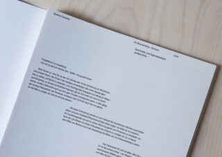 Eine Nahaufnahme eines deutschen Textdokuments mit dem Titel „Posthumer Text-Austausch“ von Markus Rautzen, platziert auf einer hellen Holzoberfläche.