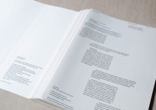 Ein Stapel offener Seiten mit in schwarzer Tinte auf weißem Papier gedrucktem Text liegt auf einer hellen Oberfläche ausgebreitet.