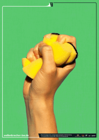 Eine Hand drückt einen gelben Schwamm fest vor einem schlichten grünen Hintergrund.