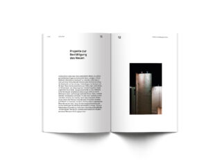 Aufgeschlagenes Buch mit einer linken Seite mit deutschem Text und einer Überschrift und einer rechten Seite mit einem Foto hoher Betonkonstruktionen vor dunklem Hintergrund.