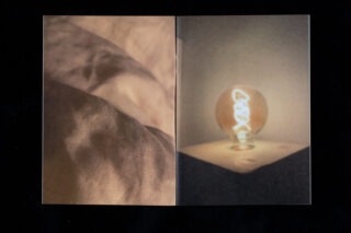 Links eine Nahaufnahme von zerknittertem Stoff und rechts eine leuchtende Glühbirne auf einer Holzoberfläche, beide mit einem weichen, warmen und leicht verschwommenen Aussehen.