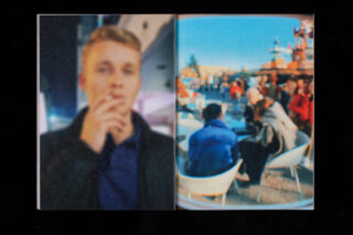 Ein verschwommenes Bild einer Person mit einer Zigarette auf der linken Seite und einer Gruppe von Menschen, die an Tischen im Freien sitzen, auf der rechten Seite, beide unscharf.