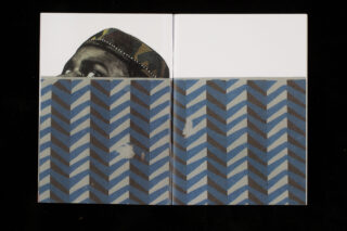 Hinter dem blau-grauen Papier mit Zickzackmuster ist eine Person mit einem gemusterten Hut teilweise sichtbar; nur die Augen und die Stirn sind zu sehen.