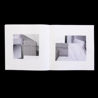 Ein offenes Buch zeigt auf beiden Seiten abstrakte geometrische Collagen in Schwarzweiß mit Mustern, Gittern und verschwommenen Texturen auf einem schlichten Hintergrund.