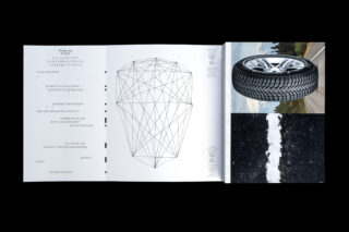 Eine aufgeschlagene Zeitschrift zeigt auf der linken Seite ein geometrisches Diagramm und einen deutschen Text, auf der rechten Seite ein umgedrehtes Foto eines Autoreifens und einer Straße.