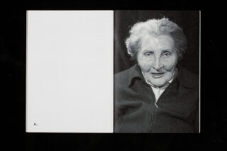 Ein offenes Buch mit einer leeren linken Seite mit dem Buchstaben „A.“ und einem Schwarzweißporträt einer älteren Frau auf der rechten Seite.