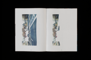 Ein offenes Buch mit zwei Seiten, jede mit einem identischen, vertikal ausgerichteten Foto einer Stadtstraße mit Gebäuden und geparkten Autos.