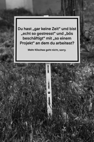 Auf einem Schild auf einer Rasenfläche steht auf Deutsch: „Sie haben ‚keine Zeit‘, sind ‚so gestresst‘ und ‚beschäftigt‘ mit ‚irgendeinem Projekt‘.“ Klischeehafter geht es nicht, tut mir leid.